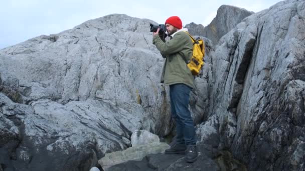 Fotógrafo de naturaleza profesional con cámara en la cima de la montaña mirando a su alrededor y tomando fotos . — Vídeos de Stock