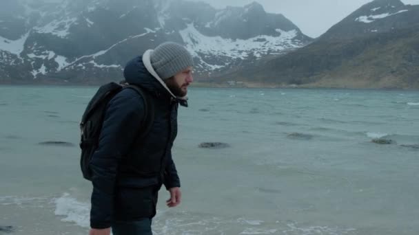 Young man walking alone on the beach on a winter day. strong wind — Stock Video