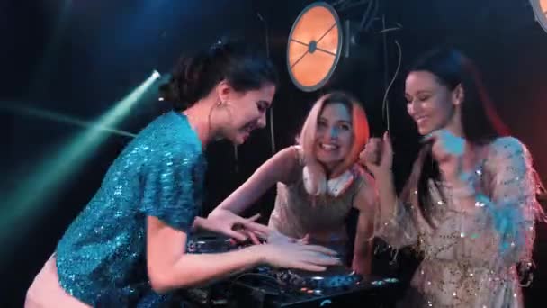 Τρία χαμογελαστά νεαρά κορίτσια παίζουν μουσική σε πικάπ και τραγουδούν τραγούδια. DJ με πικάπ και ξανθούς τραγουδιστές. Ελκυστικά γυναικεία μοντέλα. — Αρχείο Βίντεο