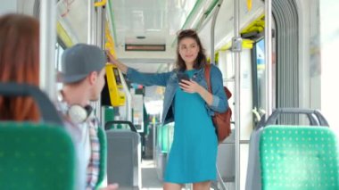 Tramvaydaki toplu taşımacılık için akıllı telefonla ödeme yapan bir kadın.