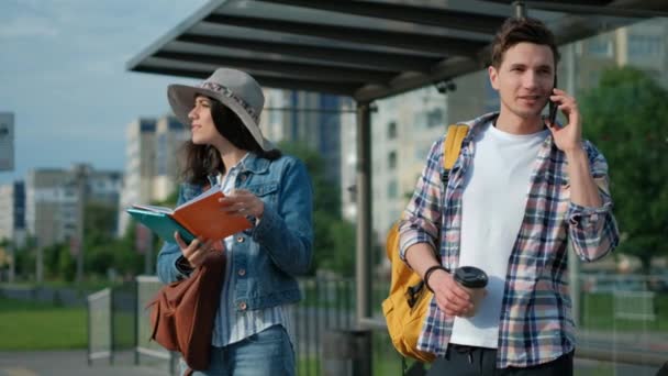 Young man and girl. Standing on the Bus Stop. Sun is Shining. Man Using his Mobile Phone. Waiting for his Tram. City Lifestyle. — Stock Video