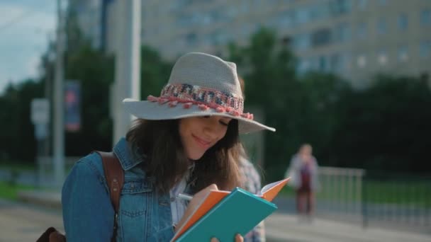 Junge Studentin an einer Bushaltestelle — Stockvideo