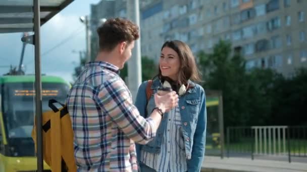 Пара спілкується під час очікування на трамвайній зупинці — стокове відео