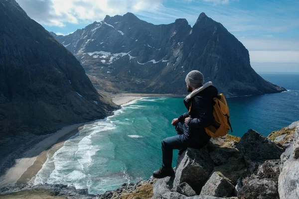 Mies istuu kallion reunalla yksin nauttien ilmakuva reppu elämäntapa matka seikkailu ulkona lomat Norjassa päälle Reinebringen vuori . kuvapankin valokuva
