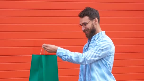 Man with beard and mustache holds shopping bags, red background. Guy shopping on sales season with discounts. Man caucasian hipster holding bunch of shopping bags. Shopping concept. — Stock Video