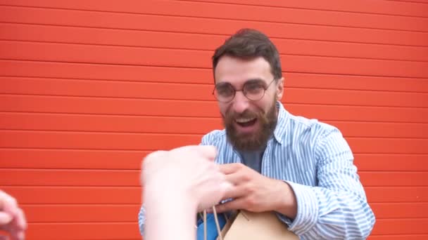 안경을 쓴 행복한 수염을 가진 남자가 손에 가방을 들고 있는 초상화. 상점에서 쇼핑 — 비디오