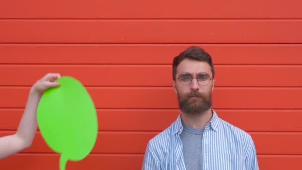 赤い背景に対話スピーチや長方形の緑のバブルスピーチを持つ幸せな男. — ストック動画