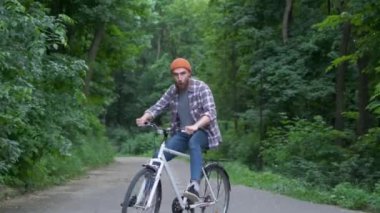 Bisikletli genç adam açık hava eğlencesi yaşıyor. retro vintage tarzı görüntü. Mutlu hipster adam yolda bisiklet sürerken gülümseme. Bisiklet ve macera seyahat yaşam tarzı