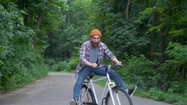 Fiatal férfi kerékpárral, amelynek szabadtéri szórakoztató. retro vintage stílusú kép. Happy csípő srác mosoly, míg a lovaglás kerékpáros az úton. Életmód kerékpározás és Kalandozás — Stock videók