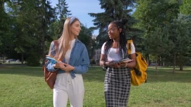 İki kadın çokuluslu arkadaşın açık hava portresi. Kızlar yazın parkta yürürler. Öğrenci yaşam tarzı, arkadaşlık kavramı
