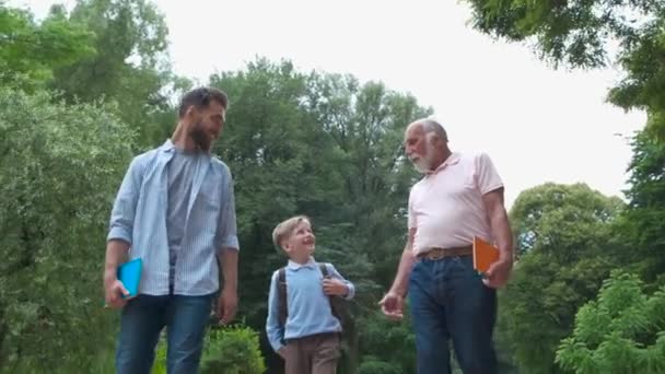 Familje generationer koncept: far, son och morfar, Utomhus, i naturen, njuter av sin kvalitetstid tillsammans, allt i fint slitage ta barn till skolan. — Stockvideo