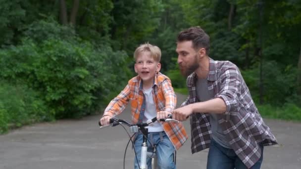 Père apprenant à son fils à faire du vélo. père et fils concept de famille . — Video