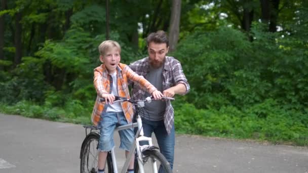 父は息子に自転車に乗るように教えた。父と息子の家族の概念. — ストック動画