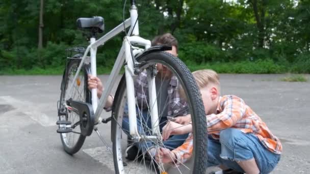 Porträtt av Lille pojke och hans far reparera cykel — Stockvideo