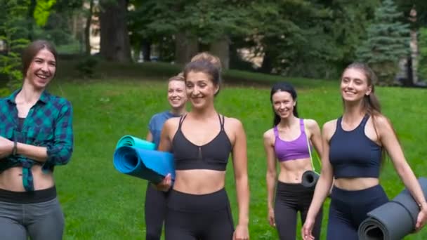 Groupe de cinq femmes souriantes actives allant à l'entraînement, tenant des tapis de yoga le matin d'été au parc. Style de vie actif concept de conditionnement physique franc. Mouvement dynamique.Sport et santé . — Video