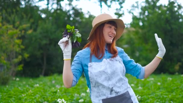 Leende kvinna trädgårdsmästare poserar med zucchini växter och tittar på kameran, jordbruk och trädgårdsskötsel koncept — Stockvideo