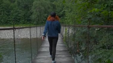 Genç kız asma köprüde yürüyor