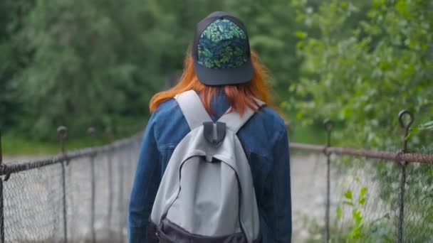 Молода дівчина гуляє на підвісному мосту — стокове відео