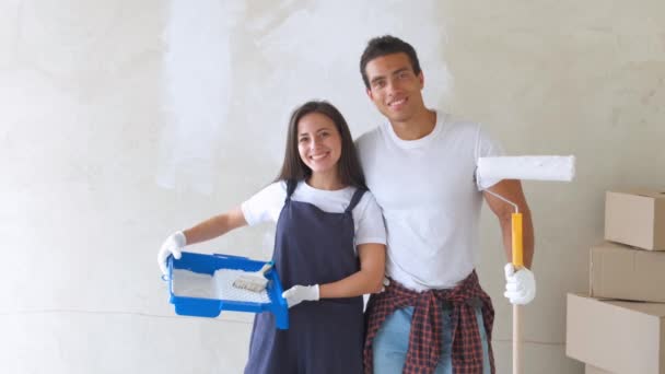 Portret młodej pary w nowym domu to malowanie i dekorowanie ściany ich domu — Wideo stockowe