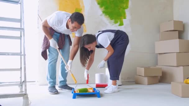 Cambio de imagen y renovación del hogar: pareja feliz joven pintando sus nuevos interiores de la casa usando rodillos de pintura — Vídeo de stock