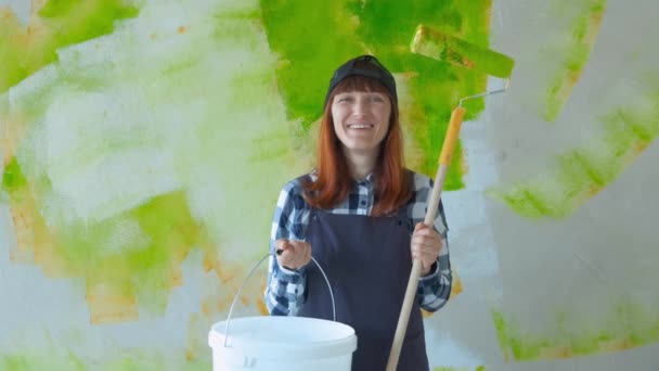 Mladá dívka provádí opravy. Ta dívka s válečkem maluje stěny. Ta holka dělá opravy a usmívá se. Namaloval zdi v domě. Konstrukce a oprava. Oprava práce