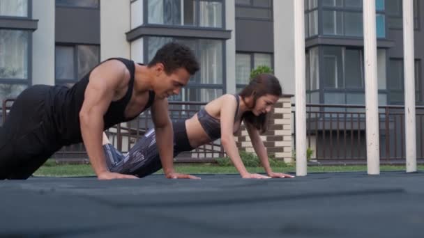 Vackra unga par arbeta ut utanför göra push ups — Stockvideo