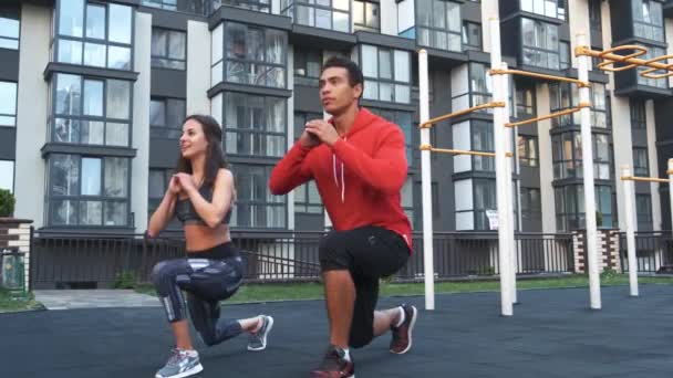 Imagem de jovem desportivo homem e mulher 20s em trajes de treino fazendo treino e agachamento juntos — Vídeo de Stock