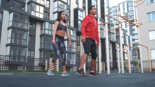 Fitness, sport, exercising and healthy lifestyle concept - man and woman doing squats outdoors in city — Stock Video