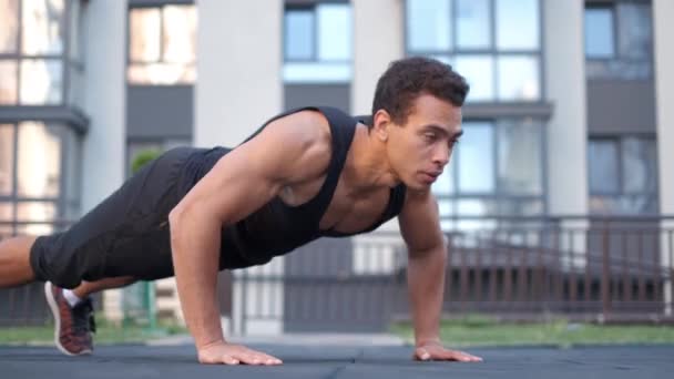 Jeune athlète masculin avec un torse nu. portrait homme fort engagé dans push-ups sur le sol, filtrant main puissante — Video
