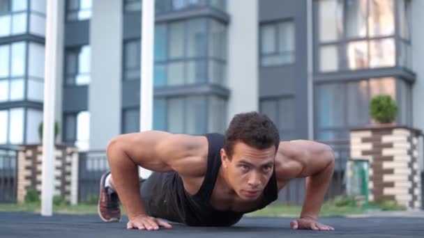 Young male athlete with a bare torso. portrait strong man engaged in push-ups on the floor, straining powerful handss — Stock Video