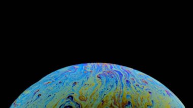 hareket halindeki bir sabun köpüğünün çok renkli irisi. siyah arka plan.