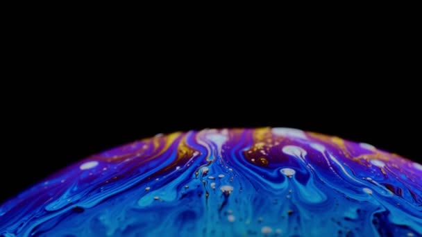 Multi-gekleurde Iris van een zeepbel in beweging. zwarte achtergrond. — Stockvideo