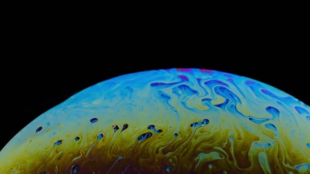 Разноцветная радужка мыльного пузыря в движении. черный фон . — стоковое видео