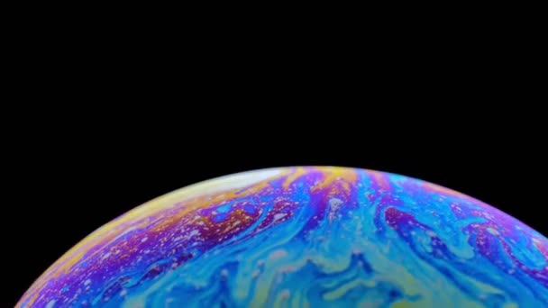 Разноцветная радужка мыльного пузыря в движении. черный фон . — стоковое видео