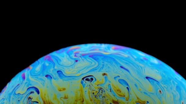 Veelkleurige regenboog kleuren van een enkele zeepbel die eruit ziet als een fantasie planeet geïsoleerd tegen een zwarte achtergrond — Stockvideo