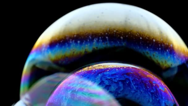 Colores multicolores del arco iris de una sola burbuja de jabón que parece un planeta de fantasía aislado sobre un fondo negro — Vídeos de Stock