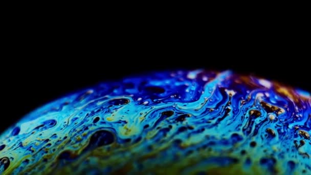 Multicolored rainbow colors of a single soap bubble that looks like a fantasy planet isolated against a black background — Stock Video