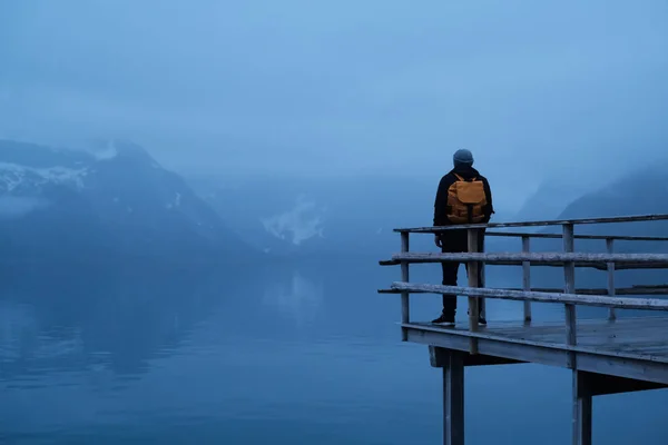 Matkustaja mies keltainen reppu seisoo yön taustalla Lofoten Reine — kuvapankkivalokuva