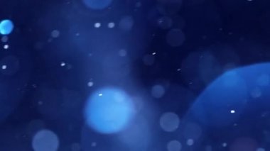 Mavi parıltılı arka plan çekimi yavaş çekimde. Suyun altındaki parçacıklar spot ışıklarında parlıyor, alan derinliği ile çekiliyor. Uzay tozu güzel bokeh soyut arkaplan