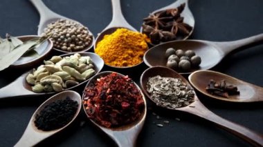 Koyu arkaplanda yemek pişirmek için çeşitli otlar ve baharatlar..