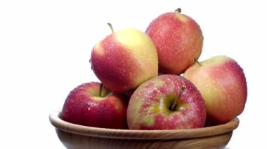 Tahta bir tabakta beyaz bir tabakta kırmızı ve sarı elmalar döner. 4K