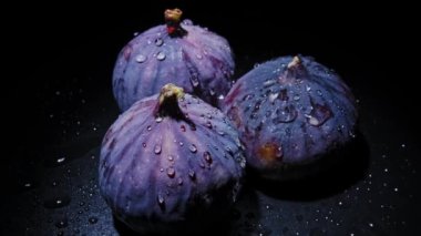 Çiy damlalı taze incirler siyah arkaplanda döner