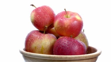 Tahta bir tabakta beyaz bir tabakta kırmızı ve sarı elmalar döner. 4K