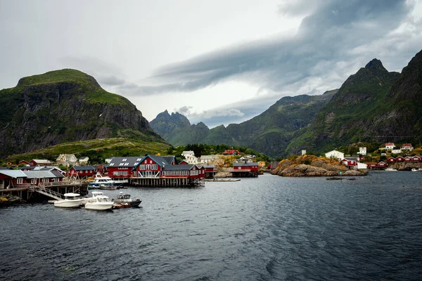 Çarpıcı ve resimli bir sahil sahnesi dramatik dağlara çarpan büyüleyici kırmızı kulübeler sergiliyor.