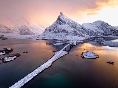 Bu resmedilmeye değer manzara karla kaplı bir dağ ve dingin sulara yansıyan bir köprü içerir.