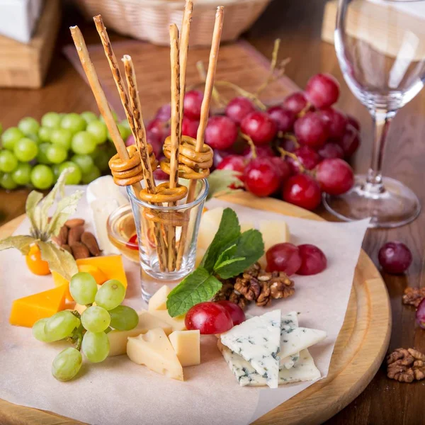 Üzüm, ekmek sopa ve bir ahşap tahta üzerinde fındık ile peynir tabakları servis.