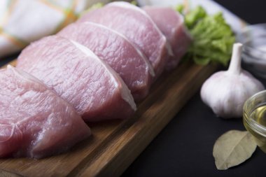 Çiğ domuz filetosu sarımsak ve yağ ile kesme tahtası.