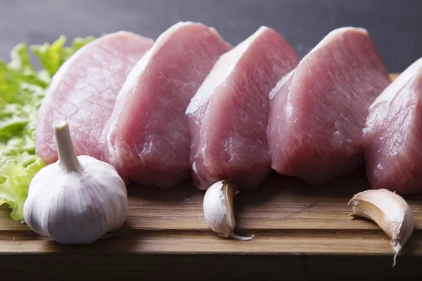 Taze Çiğ domuz fileto dilim taze sarımsak ile ahşap tahta üzerinde