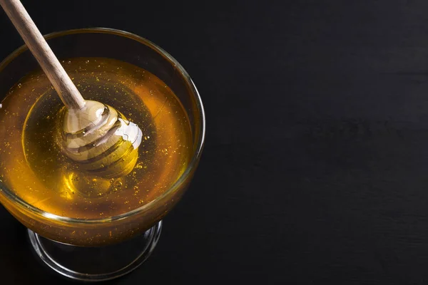 La miel en el vaso con la cacerola de miel en oscuro. Espacio para texto — Foto de Stock
