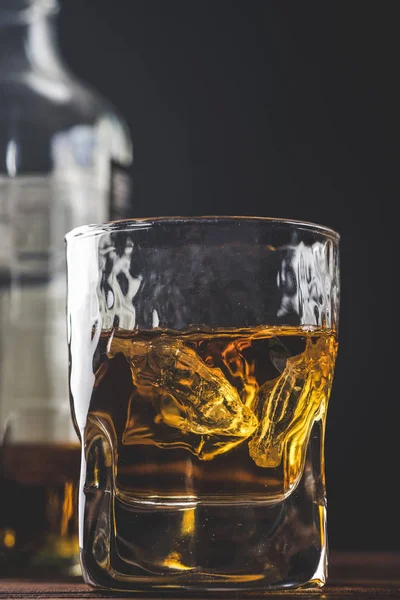 Whiskey med is i ett glas på en mörk. Närbild — Stockfoto